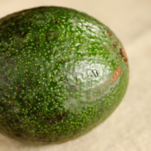 Reed Avocado: Round, dark green skin with speckled texture and subtle sheen, showcasing freshness and quality.