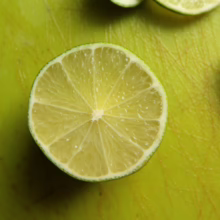 Citrus lime 'Sublime', showcasing its juicy segments and vibrant green rind on a matching green cutting board.