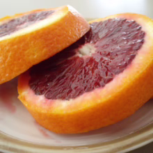 Blood Orange slices on a plate. The citrus orange is vibrant with deep red pulp and a textured orange peel.