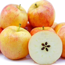 Pile of ripe Opal apples, some with red and yellow skin, one cut in half revealing the star-shaped seed core.