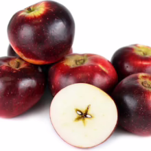Deep red ‘Liberty/Sir Prize’ apples, some whole, one sliced to show star-shaped core, against a white background