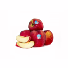 Pile of ripe Opal apples, some with blue stickers, and two apple slices in the foreground. The apples have a vibrant red color, suggesting freshness and sweetness.