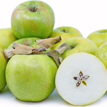 Pile of crisp, green Granny Smith apples, one cut in half to reveal a star-shaped core. The apples are fresh and vibrant, perfect for baking or a healthy snack.