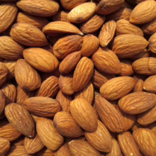 Close-up of a pile of raw almonds, showcasing their natural brown color and textured skin, perfect for snacking or baking.